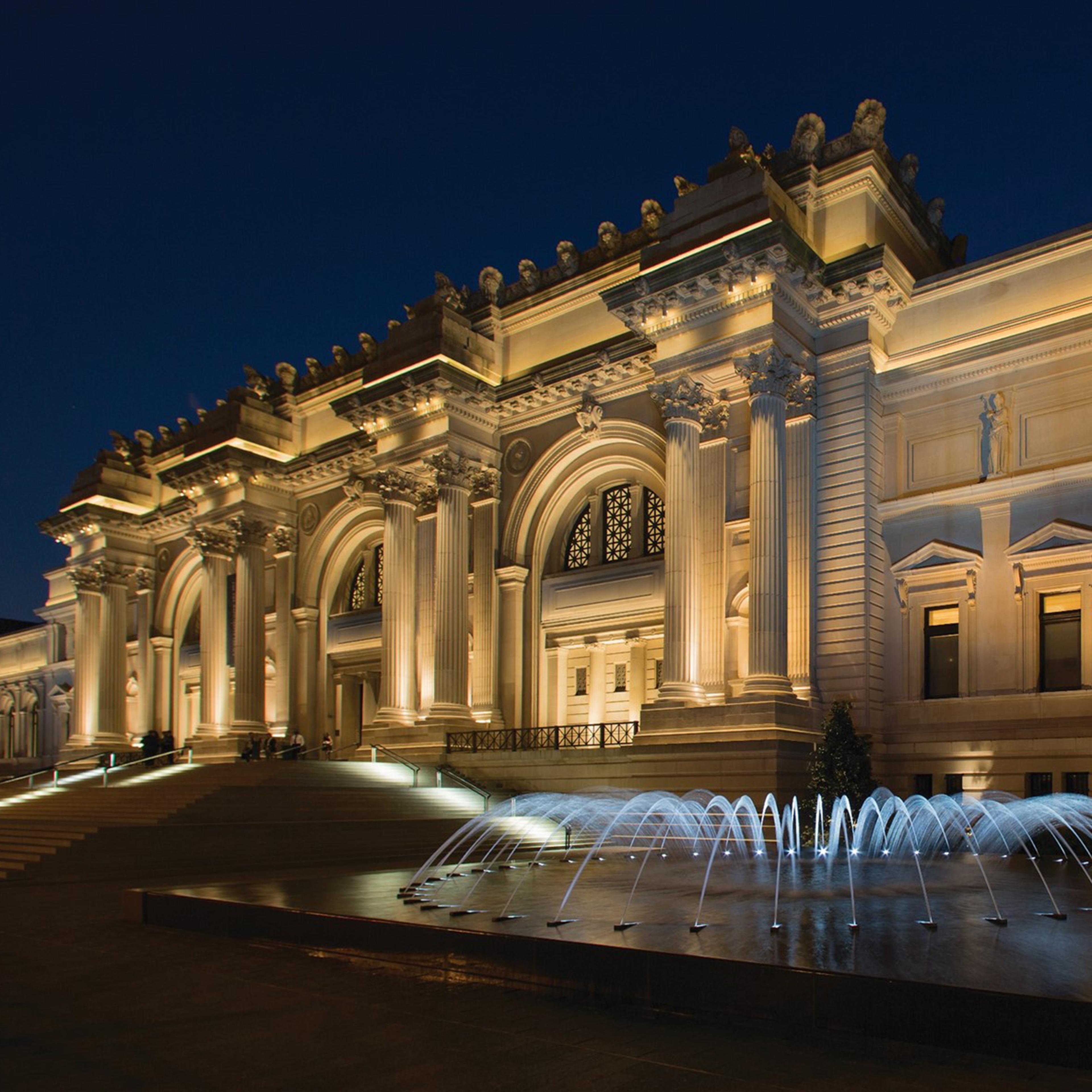 The illuminated façade of The Met Fifth Avenue at night.