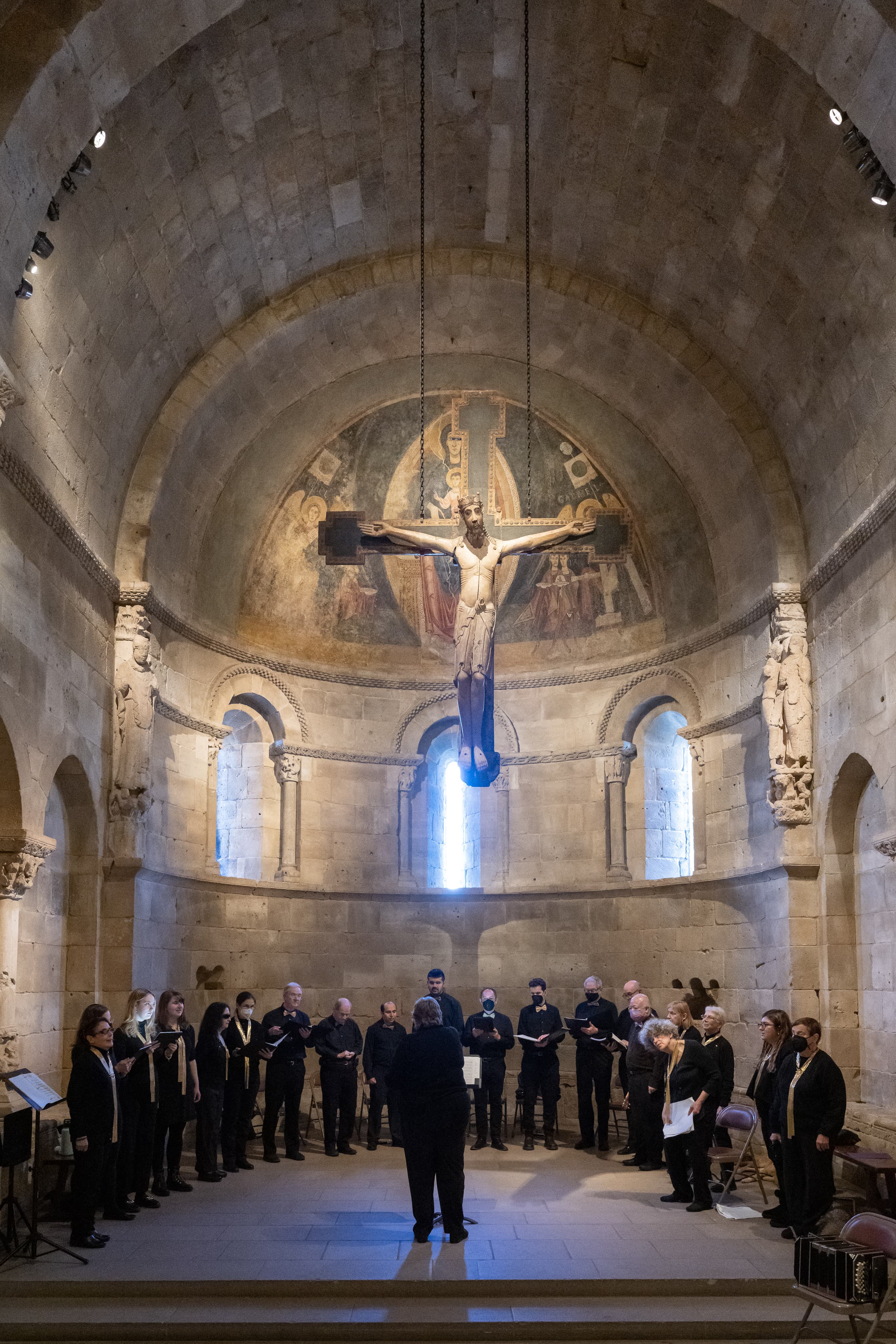 A choir group dressed in all black singing in The Fuentidueña Chapel.